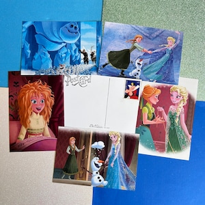 May include: A set of four postcards featuring characters from the animated film Frozen. The postcards are printed on a white background with a blue border. The first postcard features a blue ice monster. The second postcard features a scene with two characters, one in a blue dress and the other in a green dress. The third postcard features a scene with two characters, one in a blue dress and the other in a red dress. The fourth postcard features a scene with two characters, one in a blue dress and the other in a green dress. The postcards are all blank on the back.