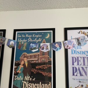 May include: A banner with images of Disney characters hangs between two framed posters. The poster on the left features a Star Wars scene. The poster on the right is for the movie Peter Pan and features the text "Walt Disney's Peter Pan" and "Color by Technicolor". The banner features images of characters from Disney movies such as Cinderella, Frozen, and The Little Mermaid.