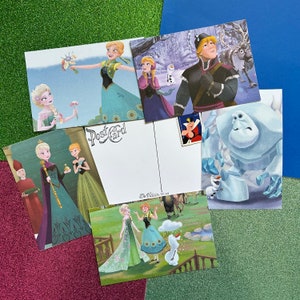 May include: A set of 6 Frozen themed postcards featuring various characters from the movie. The postcards are printed on thick cardstock and feature vibrant colors. The back of each postcard has a blank space for writing a message.