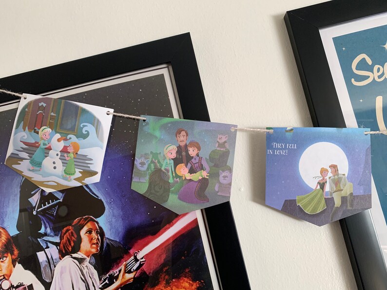 May include: A string of paper banners with illustrations from the movie Frozen. The banners feature characters from the movie, including Elsa, Anna, Kristoff, and Olaf. The text on one banner reads "They fell in love!"