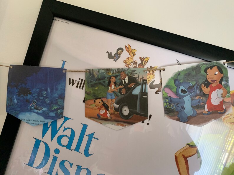 May include: A string of colorful fabric pennants with Disney characters from the movies Lilo & Stitch, The Princess and the Frog, and The Lion King. The pennants are strung together with twine and are hanging from a wall.