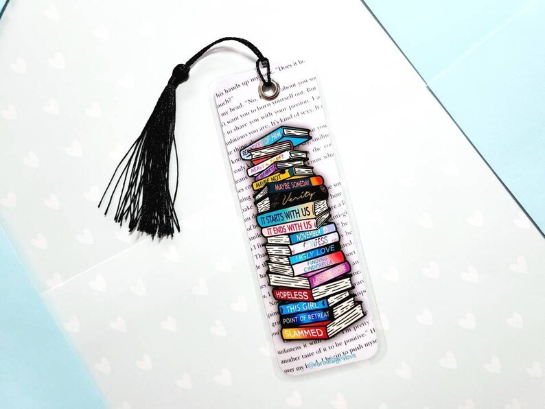K&ouml;nnte beinhalten: Ein transparentes Lesezeichen mit einem Stapel bunter B&uuml;cher, jedes mit einem anderen Titel. Die Titel sind "Maybe Someday", "Verity", "It Starts With Us", "It Ends With Us", "November 9", "Ugly Love", "The Kissing Booth", "Cinderalla", "Hopeless", "This Girl", "Point of Retreat" und "Slammed".
