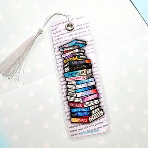K&ouml;nnte beinhalten: Ein transparentes Lesezeichen mit einem Stapel bunter B&uuml;cher, jedes mit einem anderen Buchtitel. Die Titel beinhalten "Maybe Someday", "Verity", "It Starts With Us", "It Ends With Us", "November", "Confess", "Ugly Love", "Finding Cinderella", "Hopeless", "This Girl", "Point of Retreat" und "Slammed".