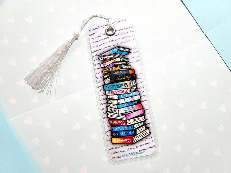 K&ouml;nnte beinhalten: Ein transparentes Lesezeichen mit einem Stapel bunter B&uuml;cher, jedes mit einem anderen Buchtitel. Die Titel beinhalten "Maybe Someday", "Verity", "It Starts With Us", "It Ends With Us", "November", "Confess", "Ugly Love", "Finding Cinderella", "Hopeless", "This Girl", "Point of Retreat" und "Slammed".