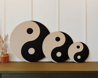 Puede incluir: Tres piezas de decoración de pared redonda de madera en diferentes tamaños, cada una con un símbolo yin yang negro y beige.