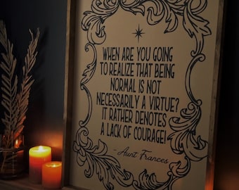 May include: A framed print with a black and white design of a decorative border and text that reads "When are you going to realize that being normal is not necessarily a virtue? It rather denotes a lack of courage! - Aunt Frances"