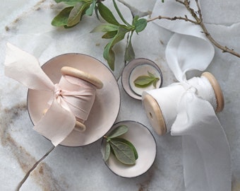 Styling dish set, a set of four miniature enamelled styling dishes in a pale soft almond shade with hand-dyed almond blush silk ribbon