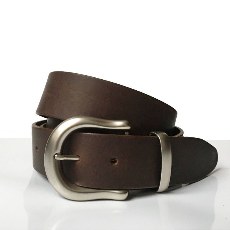May include: A brown leather belt with a silver buckle. The belt is folded in half and the buckle is visible in the center of the image.