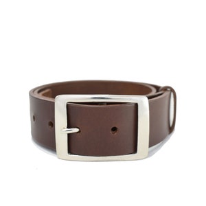 May include: A brown leather belt with a silver buckle. The belt has five holes for adjusting the fit.