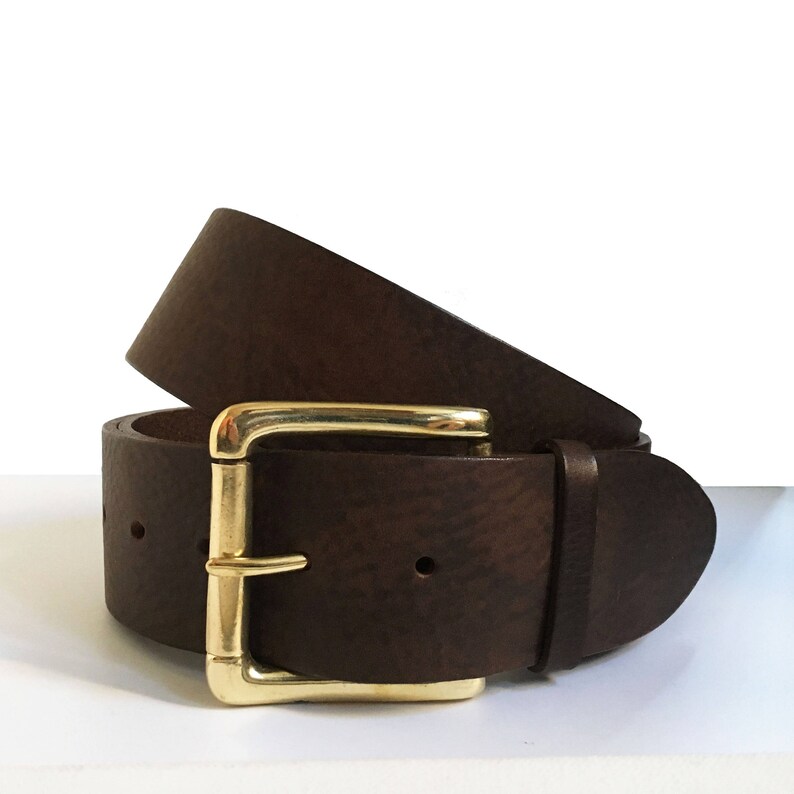 May include: A brown leather belt with a gold buckle. The belt is folded in half, showing the buckle and the leather.