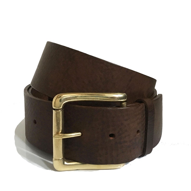 May include: A brown leather belt with a gold buckle. The belt is rolled up and the buckle is visible.