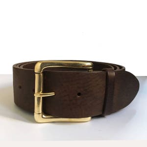 May include: A brown leather belt with a gold buckle. The belt is made from thick, textured leather and has a simple, classic design.