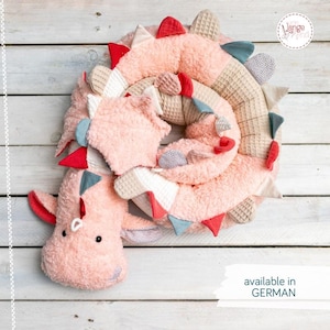 Puede incluir: Un juguete de peluche largo y enrollado con forma de dragón, hecho de tela suave y texturizada de color melocotón. Presenta un patrón de tejido de gofre en la espalda, pequeñas púas triangulares en rojo, azul y gris, y ojos negros bordados.