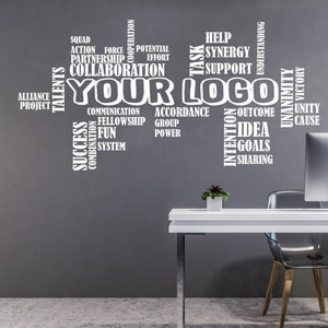 May include: White wall decal with the words "Your Logo" in large letters surrounded by smaller words related to teamwork, success, and collaboration. The decal is displayed on a gray wall in an office setting with a white desk, a clear chair, and a computer monitor.