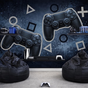 May include: A gaming room scene featuring two black bean bag chairs, a white controller on the floor, and a wall mural with large black game controllers and geometric shapes. Shelves hold gaming accessories.