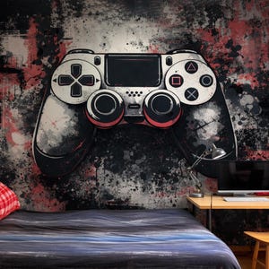 Könnte beinhalten: Ein großes, stilisiertes Bild eines Videospiel-Controllers dominiert eine Wand, dargestellt in Schwarz, Weiß und Rot. Der Controller ist der Mittelpunkt, vor einem Hintergrund aus abstrakten Farbspritzern. Ein Bett, ein Schreibtisch und eine Lampe sind sichtbar.