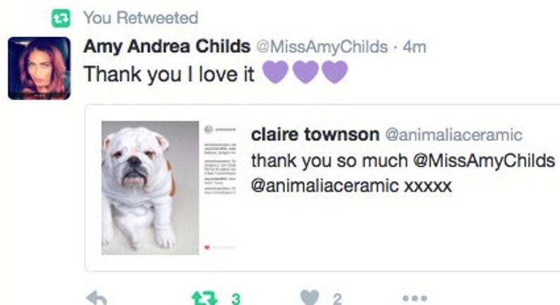 May include: A white bulldog with black spots sits on a white background. The dog is looking at the camera. The text "thank you so much @MissAmyChilds @animaliaceramic xxxx" is visible in the image.