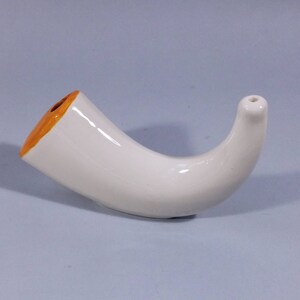 Op de afbeelding: Witte keramische vaas in de vorm van een hoorn met een oranje rand.