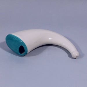 Op de afbeelding: Witte keramische hoorn met een tealblauwe rand en een klein gaatje aan de zijkant.