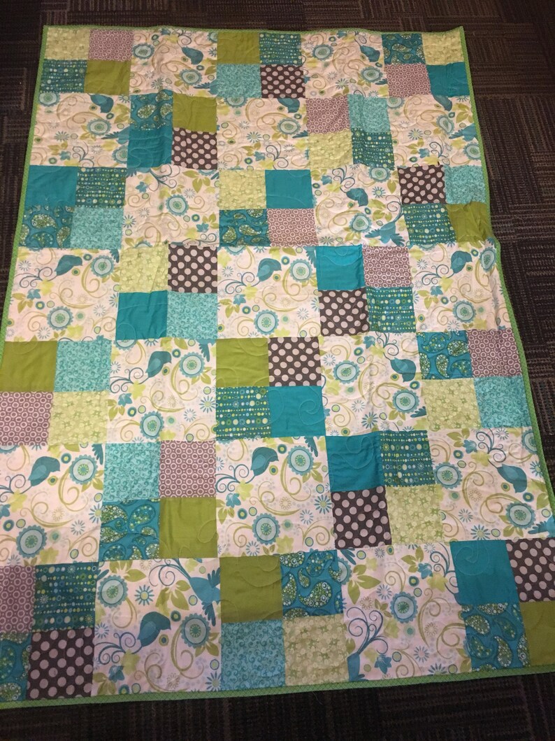 Pode incluir: Um edredom artesanal com um design de patchwork. O edredom apresenta quadrados em tons de verde-azulado, verde, castanho e branco. Alguns quadrados t&ecirc;m padr&otilde;es florais e paisley, enquanto outros t&ecirc;m bolinhas. O edredom &eacute; adornado com uma borda verde.