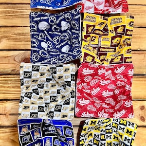 May include: Assorted fabric squares featuring collegiate and sports team logos. Designs include Penn State, Central Michigan, Indiana, and Grand Valley State. Other squares display the Detroit Red Wings and Indianapolis Colts logos.