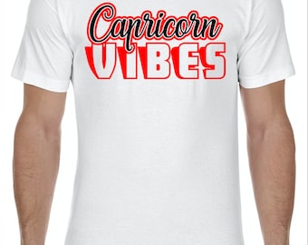 Op de afbeelding: Wit T-shirt met zwarte en rode tekst die "Capricorn Vibes" zegt.