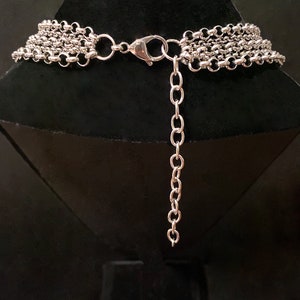 Op de afbeelding: Zilveren meerrijige ketting met een karabijn sluiting. De ketting is op een zwarte mannequinbuste.