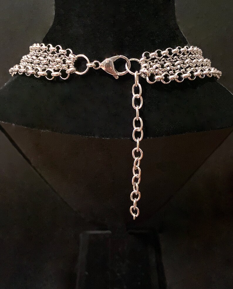 Op de afbeelding: Zilveren meerrijige ketting met een karabijn sluiting. De ketting is op een zwarte mannequinbuste.