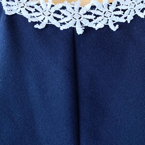 May include: A navy blue dress with a white lace trim around the neckline.