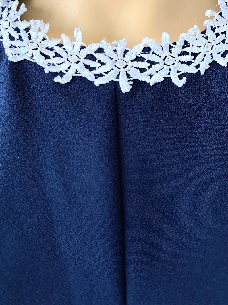 May include: A navy blue dress with a white lace trim around the neckline.