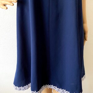 May include: A navy blue dress with a white lace trim around the hem.