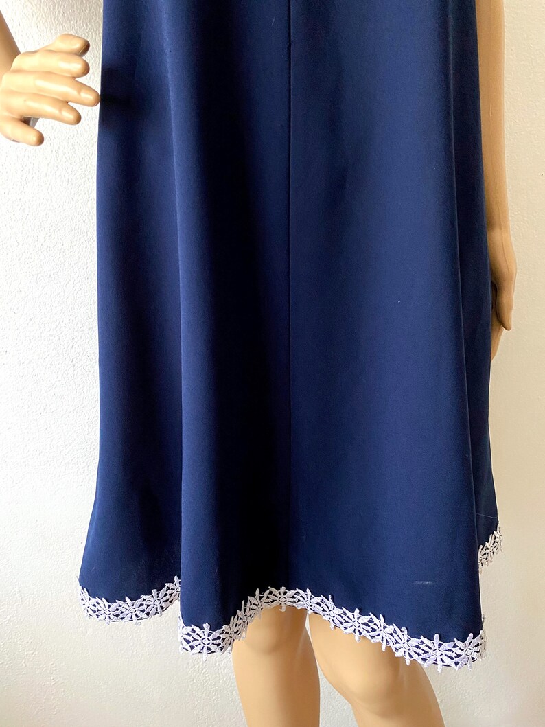 May include: A navy blue dress with a white lace trim around the hem.