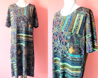 May include: A short-sleeved dress with a colorful geometric pattern in shades of blue, green, gold, and black. The dress has a round neckline and a loose fit.