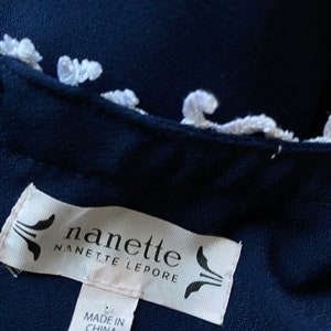 May include: A navy blue garment with a white trim and a white label that reads "nanette nanette lepore" and "made in china".