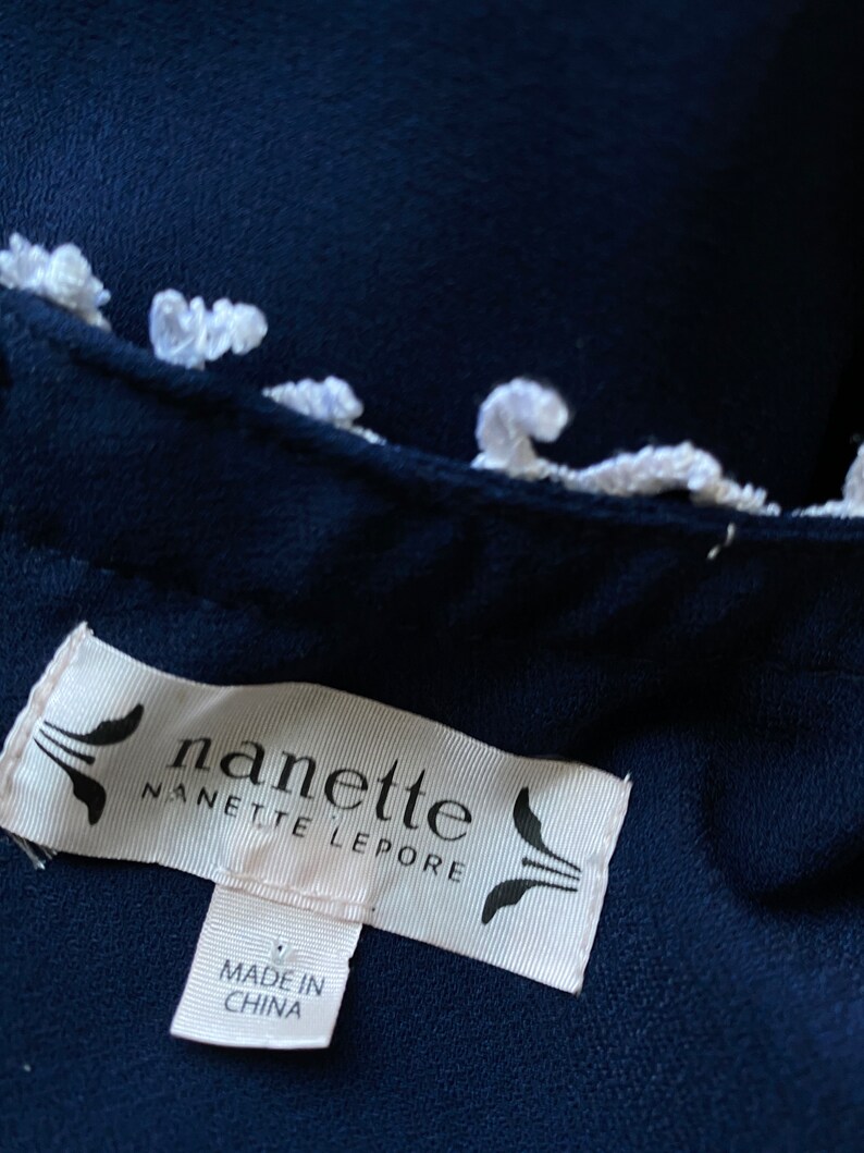 May include: A navy blue garment with a white trim and a white label that reads "nanette nanette lepore" and "made in china".