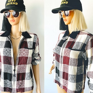 May include: A patchwork shirt in burgundy, black, and white squares, with a black collar and a zip-up front. The mannequin is wearing a black baseball cap with the text "BEST FRIEND" in gold. The shirt has a pocket on the chest.
