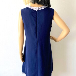 May include: A navy blue sleeveless dress with a white lace trim around the neckline and hem.