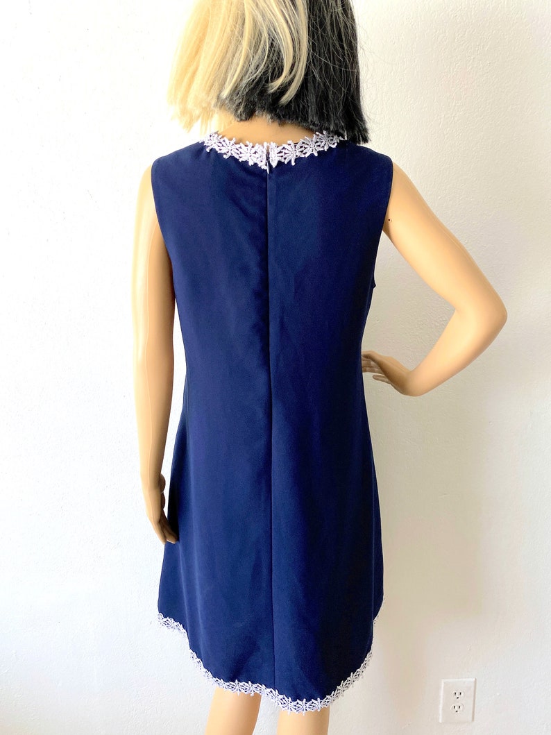 May include: A navy blue sleeveless dress with a white lace trim around the neckline and hem.