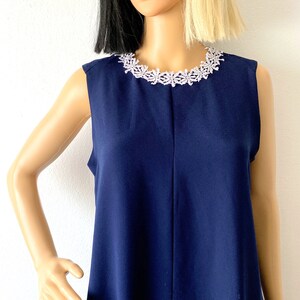 May include: A sleeveless navy blue dress with a white lace trim around the neckline.