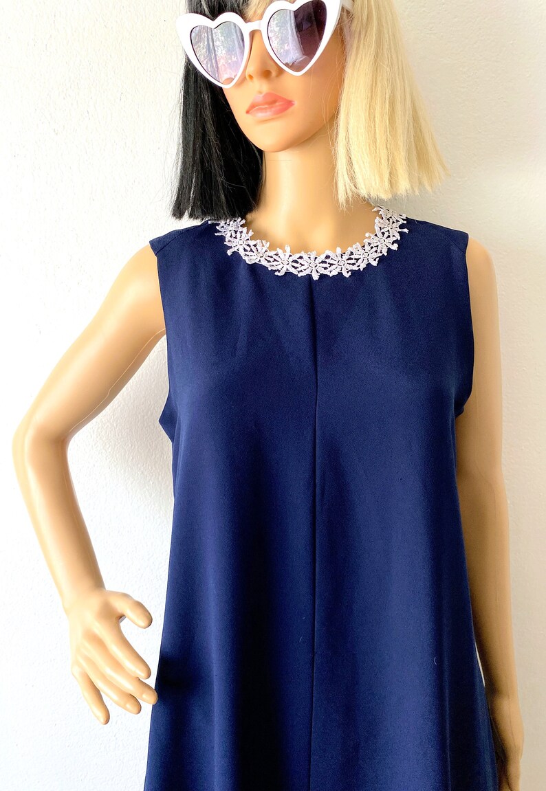 May include: A sleeveless navy blue dress with a white lace trim around the neckline.