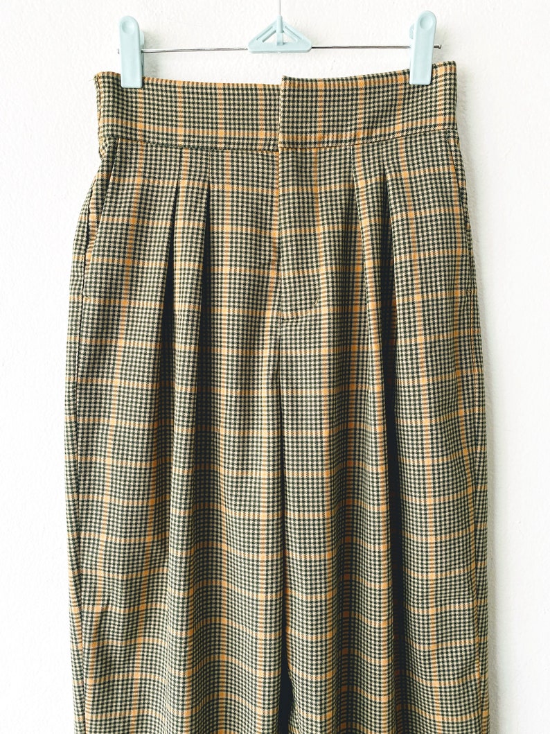 May include: A pair of high-waisted, pleated pants in a brown and yellow plaid pattern.