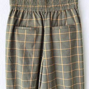 May include: A pair of brown and yellow plaid pants with an elastic waistband. The pants have two back pockets.