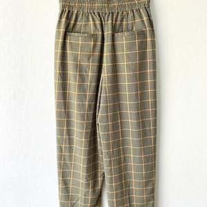 May include: A pair of brown and yellow plaid pants with an elastic waistband. The pants have a relaxed fit and are cropped at the ankle.
