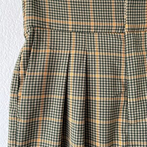 May include: A pair of high-waisted pants with a plaid pattern in shades of brown and yellow.