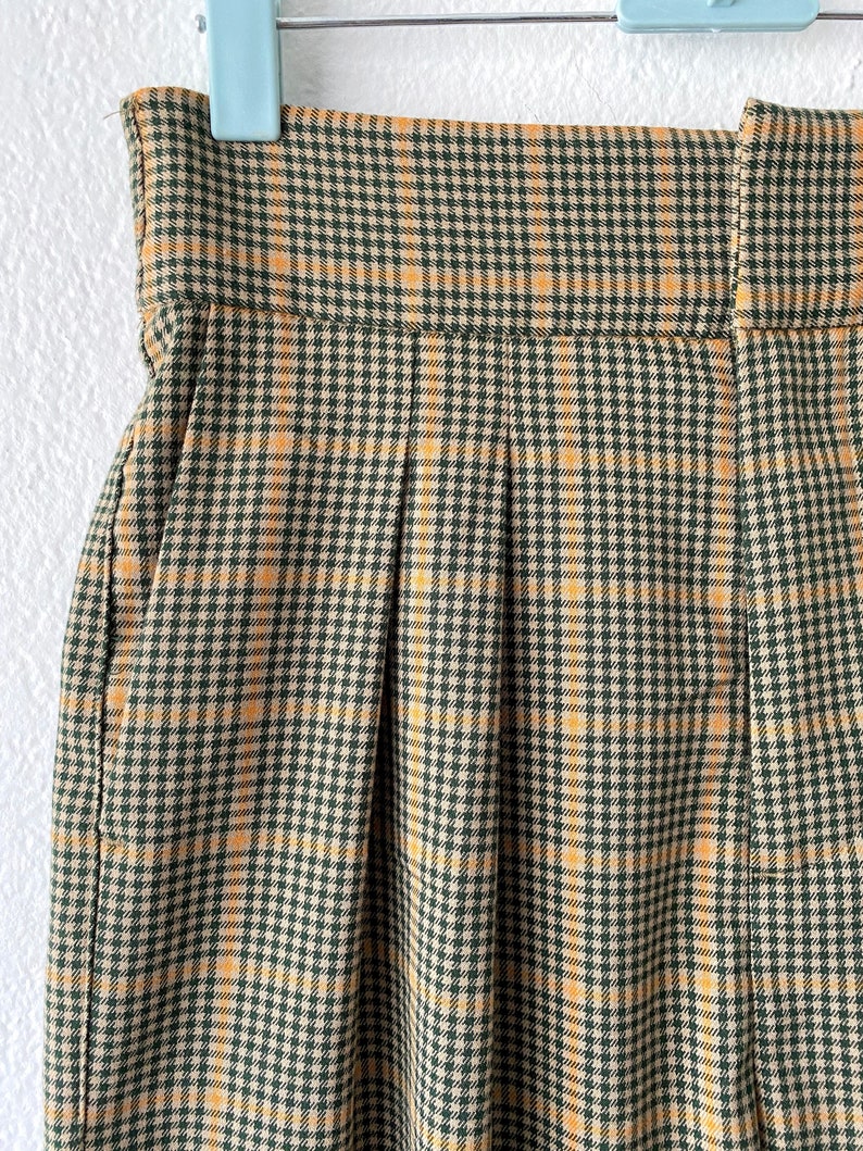 May include: A pair of high-waisted pants with a plaid pattern in shades of brown and yellow.