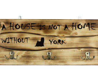 Yorkshire Terrier, a wooden wall peg, hanger with the picture of a dog and the words: "A house is not a home without..."