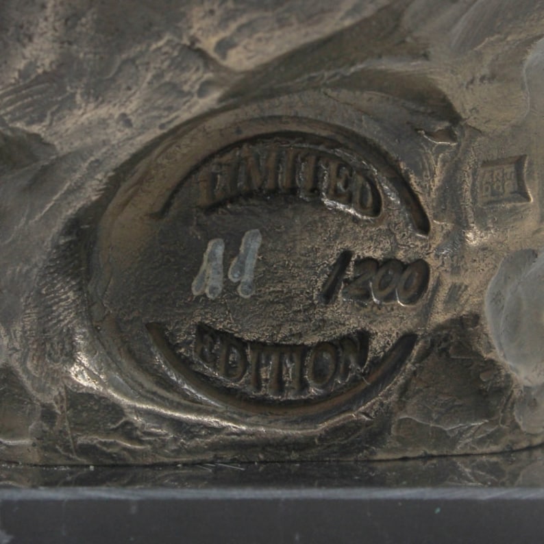 Op de afbeelding: Close-up van een ronde bronzen stempel met de tekst "LIMITED EDITION" en het nummer "44/1200" erop.
