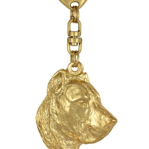 May include: Gold-colored metal keychain featuring a detailed profile of a dog's head. The keychain measures 5.2 cm by 4.3 cm and weighs 29 grams.