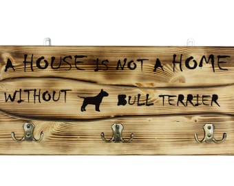 Bull Terrier, a wooden wall peg, hanger with the picture of a dog and the words: "A house is not a home without..."