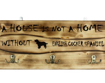 English Cocker Spaniel, a wooden wall peg, hanger with the picture of a dog and the words: "A house is not a home without..."